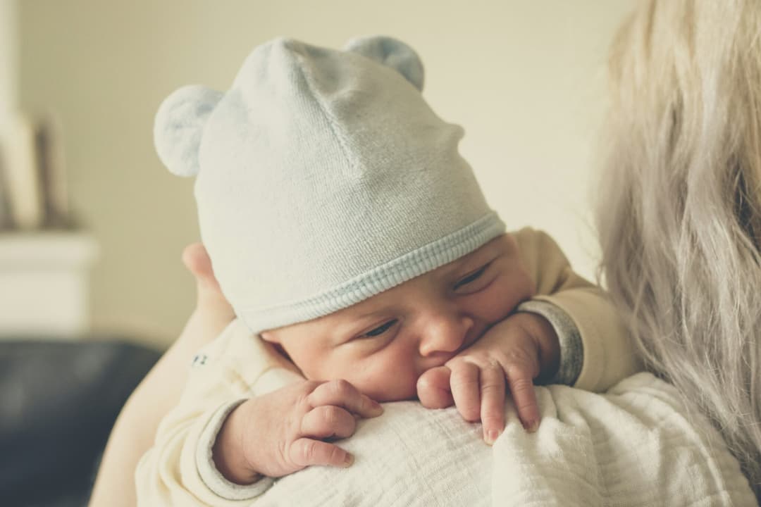 A newborn baby sleeping on a parent's shoulder